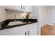 Close-up of a wet bar area featuring a sink, granite countertop, and white cabinets at 2365 Black River Falls Dr, Henderson, NV 89044