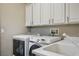 Well-lit laundry room with white cabinets, a utility sink, and modern washer and dryer set at 2785 Rosenhearty Dr, Henderson, NV 89044