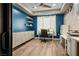 Home office with blue accent wall, floating shelves, white desk and cabinets, and wood flooring at 2785 Rosenhearty Dr, Henderson, NV 89044