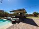 Outdoor kitchen under pergola with TV, comfortable seating, and string lights for a relaxing ambiance at 2785 Rosenhearty Dr, Henderson, NV 89044