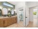 Modern bathroom with double vanity, light wood cabinets, neutral countertop, and glass enclosed shower at 2917 Golf Links Dr, Las Vegas, NV 89134