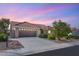 Exterior front view of the home with an attached two car garage and desert landscaping under a pink sky at 2917 Golf Links Dr, Las Vegas, NV 89134