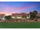 View of home's exterior with tile roof, desert landscaping, and golf course in the foreground under a pink sky at 2917 Golf Links Dr, Las Vegas, NV 89134