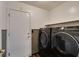Convenient laundry room featuring side-by-side washer and dryer plus a door to the outside and dark wood-look flooring at 3336 Hidden Ridge St, Las Vegas, NV 89129