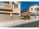 Beige townhouses feature multi-car garages, decorative stone accents and a well-maintained landscape at 3609 Indigo Flower St # 1, North Las Vegas, NV 89084