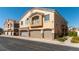 A tan two-story townhouse featuring a private balcony and individual one-car garages at 3609 Indigo Flower St # 1, North Las Vegas, NV 89084