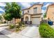Charming two-story home with stucco exterior, a blue front door, desert landscaping, and attached garage at 4249 Fleet Dancer St, Las Vegas, NV 89129