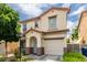 Charming two-story home with stucco exterior, a blue front door, desert landscaping, and attached garage at 4249 Fleet Dancer St, Las Vegas, NV 89129