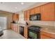 Galley kitchen featuring wooden cabinets, granite counters, and a full suite of black appliances at 4535 Mission Meadow Cir, Las Vegas, NV 89139