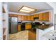 Galley kitchen with stainless steel refrigerator, black appliances, breakfast bar, and light wood cabinets at 4655 Gold Dust Ave # 206, Las Vegas, NV 89120