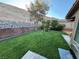 This backyard features a large lawn, mature landscaping, and a brick retaining wall at 574 Desert Tortoise Way, Mesquite, NV 89027