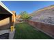 A charming backyard featuring a well-kept lawn, shade tree, and a sturdy brick retaining wall at 574 Desert Tortoise Way, Mesquite, NV 89027