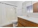 Bright bathroom featuring a shower-tub combo with a white shower surround and wood-finish vanity at 6553 Baywood Ave, Las Vegas, NV 89103