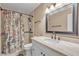 Bright bathroom with a shower, floral curtain, and a granite-style vanity at 7197 Sixshooter Dr, Las Vegas, NV 89119