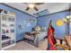 Comfortable bedroom with blue walls, featuring a ceiling fan and unique decor at 7197 Sixshooter Dr, Las Vegas, NV 89119
