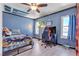 Blue bedroom with a ceiling fan, laminate wood floors, and natural light from two windows at 7197 Sixshooter Dr, Las Vegas, NV 89119