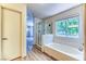 Bright bathroom with a soaking tub, a glass-enclosed shower, and wood-look floors at 7900 Dutch Canyon Ct, Las Vegas, NV 89131