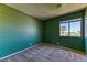 Cozy bedroom with textured green walls, neutral carpet, and a window with a view of palm trees at 7900 Dutch Canyon Ct, Las Vegas, NV 89131