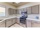 Well-lit kitchen with modern appliances, gray cabinets, white countertops, and light wood-look floors at 7900 Dutch Canyon Ct, Las Vegas, NV 89131