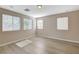 Sunlit bedroom has wood-look floors, neutral walls, and three bright windows with tree views at 8307 Fort Hallock Ave, Las Vegas, NV 89131