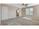 Neutral carpeted main bedroom featuring a ceiling fan, natural light, and access to the en-suite bathroom at 8307 Fort Hallock Ave, Las Vegas, NV 89131