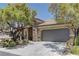 Attractive single-story home with a two-car garage, stone accents, and lush trees at 9120 Parkstone Ave, Las Vegas, NV 89178