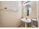 Small powder room features a pedestal sink, round mirror, and neutral wall color scheme at 10456 Prairie Schooner Ave, Las Vegas, NV 89129