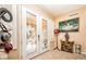 Bright foyer with decorative glass double doors, adjacent to an elegant hat rack and beautiful artwork at 10798 Tapestry Winds St, Las Vegas, NV 89141