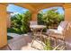 Outdoor patio featuring a cozy seating area with a table and chairs, surrounded by lush greenery at 10798 Tapestry Winds St, Las Vegas, NV 89141