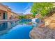 Backyard pool area features blue water, rock features, and an outdoor seating area at 10798 Tapestry Winds St, Las Vegas, NV 89141