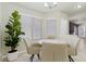 Sunlit dining area with tile flooring, a round table, and seating for four next to a potted tree and large windows at 11076 Zampino St, Las Vegas, NV 89141