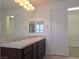 Bathroom with dual sinks, dark wood cabinetry, a large mirror, and access to a walk-in closet at 11298 Corsica Mist Ave, Las Vegas, NV 89135