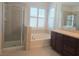 Bright bathroom featuring a soaking tub under shuttered windows, a glass shower, and a dark wood vanity at 11298 Corsica Mist Ave, Las Vegas, NV 89135