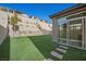 Artificial turf backyard with stone walkway and a view of the landscaped retaining wall at 12525 Lylan Ridge St, Las Vegas, NV 89138