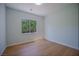 Minimalist bedroom with wood floors, white walls, and a view to nature through the window at 1371 Cumulus Ct, Henderson, NV 89014