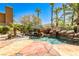 Backyard tropical pool area featuring a spa, rock waterfall feature, lush landscaping, and mature palm trees at 1737 Cypress Manor Dr, Henderson, NV 89012