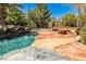 Beautiful inground pool with rock waterfall, stone bench, lush landscaping, and tropical plants at 1737 Cypress Manor Dr, Henderson, NV 89012