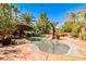 Tropical pool area with a rock waterfall feature, a spa, Tiki umbrella, and lush landscaping at 1737 Cypress Manor Dr, Henderson, NV 89012