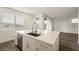 Bright kitchen featuring an island with stainless steel sink and faucet, light countertops, and a view to the living area at 175 Strada Fontana, Henderson, NV 89011