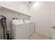 Functional laundry room features a full-size washer and dryer, upper shelving, and tile flooring at 175 Strada Fontana, Henderson, NV 89011