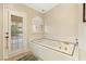 Large bathtub area with jacuzzi jets, tile flooring, and a door to the backyard at 1913 Madagascar Ln, Las Vegas, NV 89117