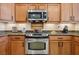 Close-up of the stainless steel range surrounded by wood cabinets and granite countertops at 2453 Vivid Sky Pl, Henderson, NV 89044