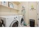 Functional laundry room with front-load washer and dryer, storage shelf, and cleaning supplies at 2453 Vivid Sky Pl, Henderson, NV 89044
