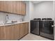 A modern laundry room features wood-tone cabinets, countertop, sink, and stainless steel washer and dryer at 40 Heron Harbour Dr, Henderson, NV 89011