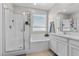 Bright bathroom features a glass-enclosed shower and separate tub with window at 4030 Midnight Crest Ave, North Las Vegas, NV 89031
