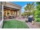 Relaxing outdoor patio area with comfortable seating, lush landscaping, and artificial turf at 4286 Pacifico Ln, Las Vegas, NV 89135