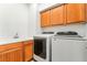 Convenient laundry area with sink, wooden cabinets, washer, and dryer units at 512 Los Dolces St, Las Vegas, NV 89138