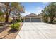 Home exterior with a three-car garage, mature trees, and desert landscaping at 5232 Saranac Rd, Las Vegas, NV 89130
