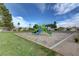 Community playground featuring climbing structure and slides surrounded by well maintained green grass and trees at 5236 Krista Alethea St, North Las Vegas, NV 89031
