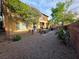 Spacious backyard with gravel, patio area, seating, grill, mature trees, and partial wall for privacy at 5507 Gemini Bridges St, Las Vegas, NV 89130